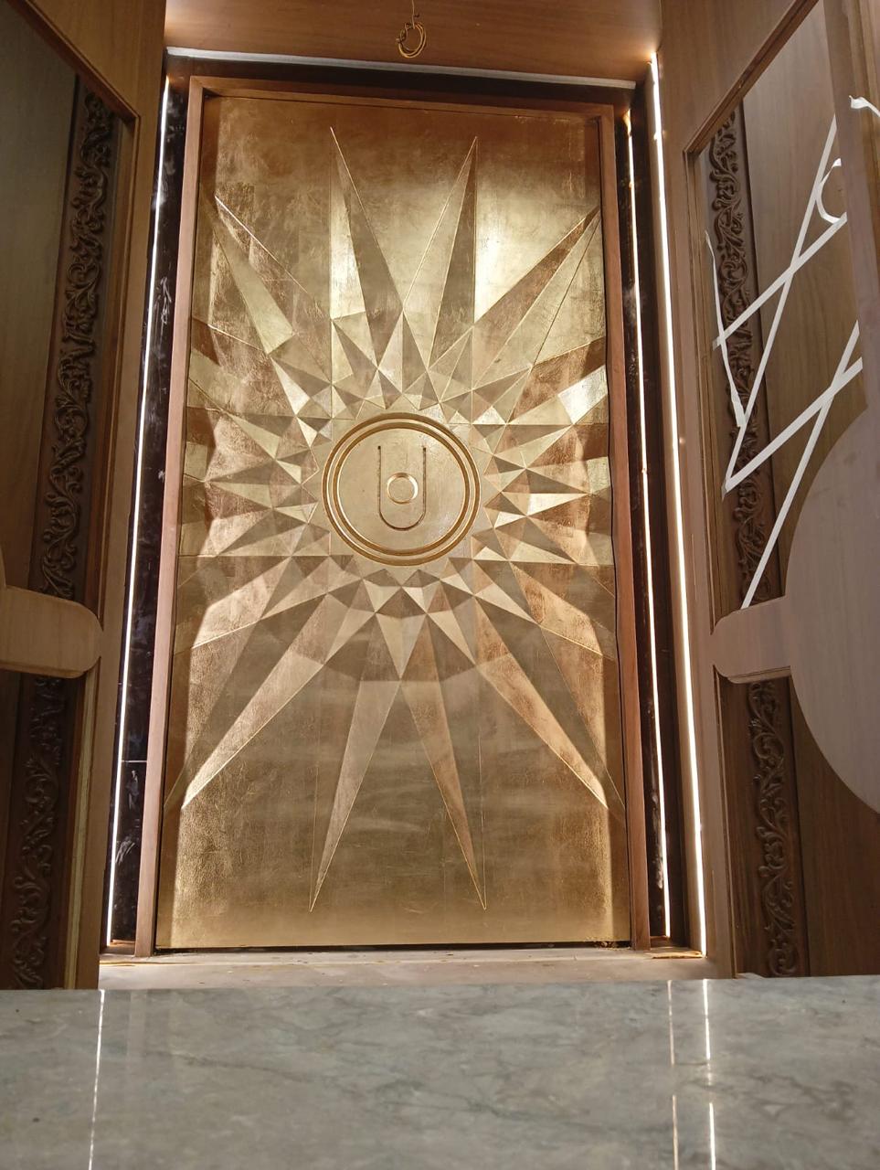 Gold metallic sunburst panel framed by carved wood and vertical lighting