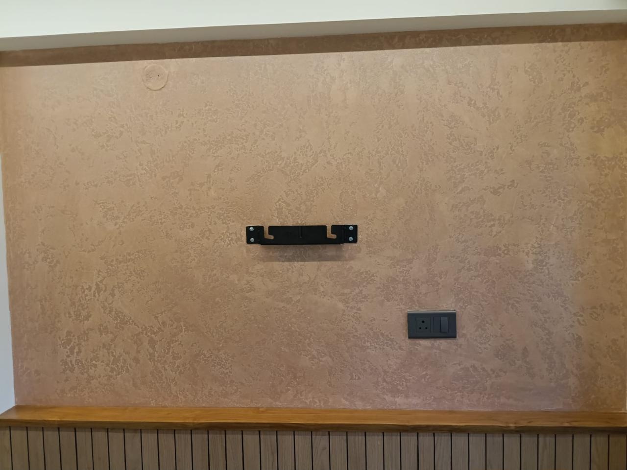Warm decorative plaster feature wall above a fluted wood base