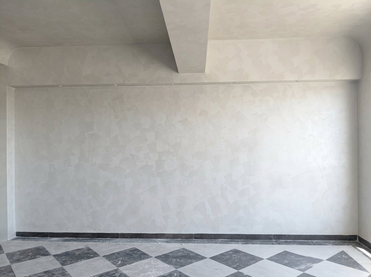 Subtle pale geometric plaster wall above a grey patterned floor