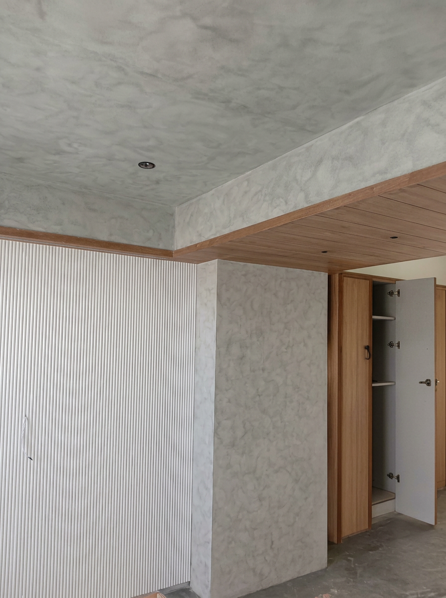 Grey mineral-textured ceiling and walls with white fluting and wooden ceiling panels
