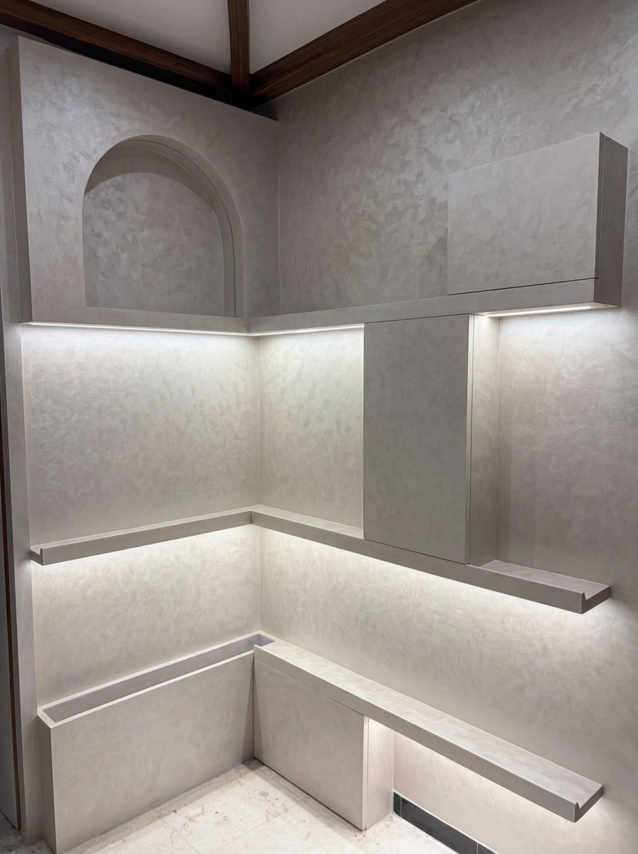 Pale textured corner walls with an arched detail and illuminated projecting shelves