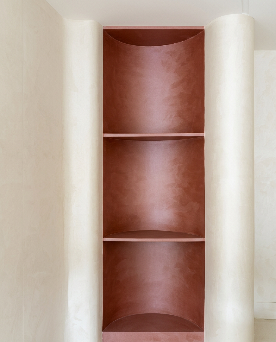 Terracotta recessed shelves framed by pale curved plaster walls